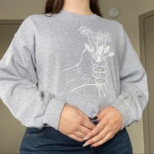 hand holding flowers grey graphic sweatshirt